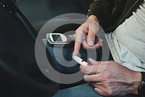 Lancet pen and glucometer in the hands of a man in a car. Diabetes concept