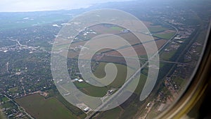 Land in the porthole. View of the ground from the airplane window. Multi-colored fields from above. Flight in a