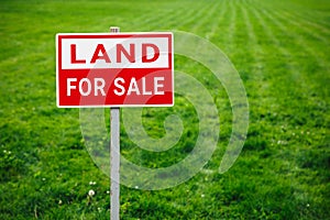 Land for sale plate sign, green lawn background