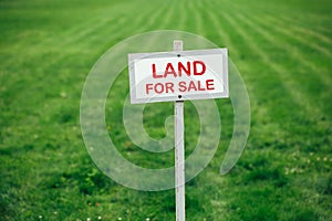 Land for sale sign against trimmed lawn background