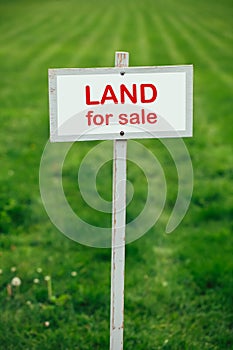 Land for sale sign against trimmed lawn background