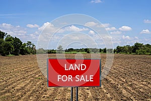 Land for sale sign against trimmed lawn background. Empty dry cracked swamp reclamation soil, land plot for housing construction