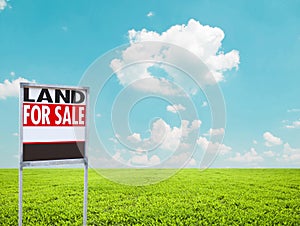 Land for sale sign on empty green field