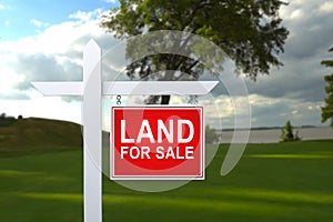 LAND FOR SALE SIGN on empty meadow - Real estate conceptual image.