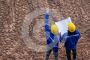 Land surveyor team standing working together at construction field consult study looking building location with floor plan