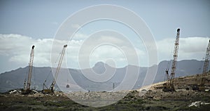 Landfill, crane and trash outdoor for waste, dirt and tractor with industrial background and blue sky. Garbage, site and