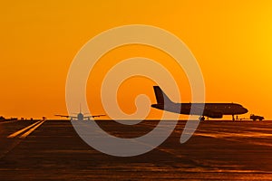 Landing airplanes against colorful sky at sunset. Travel background with passenger plane. Evacuation