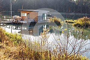 Landing stage house on wooden pier in water in forest in evening