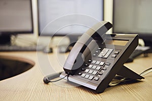 Landline phone on office desk with computer monitors and keyboards