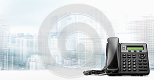 Landline telephone with VOIP on white table on blurred city background. customer service support, call center concept. Modern VoIP