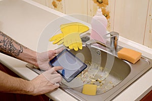 The landlord uses the tablet to call a cleaner in order to clean the clogged kitchen sink