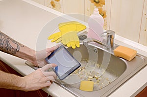 The landlord uses the tablet to call a cleaner in order to clean the clogged kitchen sink