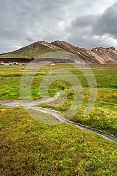 Landmannalaugar, Iceland. Camping site and mountain hut with many tents and beautiful Icelandic landscape of colorful rainbow