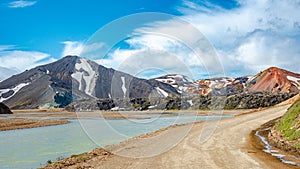 Landmannalaugar, Iceland, Gravel road near water stream at camping and mountain hut, Icelandic landscape of colorful rainbow