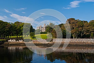Landmark and attraction. Lews Castle in Stornoway, United Kingdom seen from sea harbor. Castle with green grounds on photo