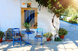 Landmark photo of blue chairs with table in typical Greek town