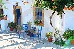 Landmark photo of blue chairs with table in typical Greek town