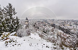 Landmark Uhrturm on hill Schlossberg in Graz on snowy winterday