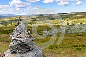 Landscape along the peer gynt vegen road with a cairn in front