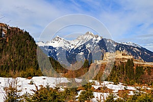 Landscape in the Alps with fresh green mountain pastures and snow-capped mountain tops in the background. Tyrol, Austria