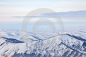 Landscape in the Altai mountains with snow-capped peaks under a blue sky with clouds in winter. White snow and calm