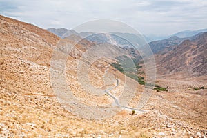 Landscape of the amazing colorful red mountains over the thin curved asphalt road in rocky canyon