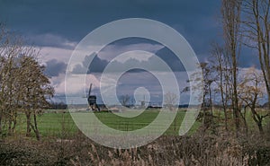 Landscape with ancient windmills in the Netherlands in gloomy spring weather. Stormy day over Dutch village of Streefkerk