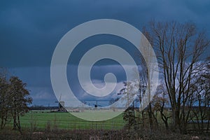 Landscape with ancient windmills in the Netherlands in gloomy spring weather. Stormy day over Dutch village of Streefkerk