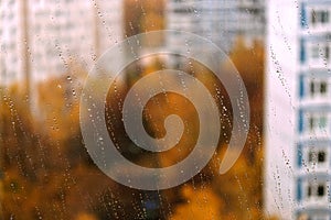 Landscape with autumn in the city view through transparent window glass with focus on rain drops