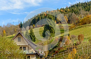 Landscape autumn countryside with wooden farmhouses on green hill and mountains in the background,Germany