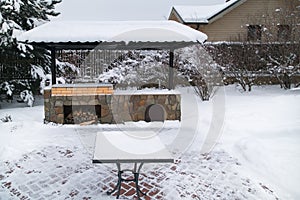 Landscape with barbeque area, snowbanks of white snow, pine trees in country garden.