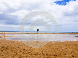 Landscape of beach and sea with lifeguard post and green vandera allowing the bath. Canary Islands, Spain