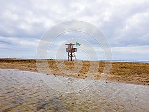 Landscape of beach and sea with lifeguard post and green vandera allowing the bath. Canary Islands, Spain