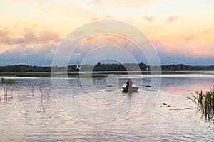 Landscape Beautiful lake in the evening with rower on the oars and small church on the horizon