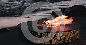 The landscape of the beautiful metal round a fireplace on the sandy coast with a tidal wave at sunset, stones