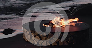 The landscape of the beautiful metal round a fireplace on the sandy coast with a tidal wave at sunset, stones