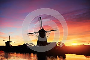 Landscape with beautiful traditional Dutch mill near water courses with fantastic sunset and reflection in water. Netherlands.