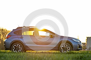 Landscape with blue off road car on green grass at sunset. Traveling by auto, adventure in wildlife, expedition or extreme travel