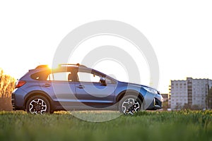 Landscape with blue off road car on green grass at sunset. Traveling by auto, adventure in wildlife, expedition or extreme travel