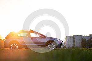 Landscape with blue off road car on green grass at sunset. Traveling by auto, adventure in wildlife, expedition or extreme travel