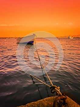 Landscape of a boat in the sea, tied with rope to the beach at Atakum Beach, a warm and orange sky. Version 2