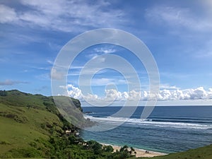 a landscape of calm beach waves from the top of the hills