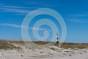 Landscape of the Cape Lookout lighthouse near Beaufort, North Carolina with sand dunes and grass in the foreground