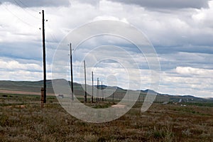 Landscape in central Mongolia close to the main road. Electricity poles along the roal. Green hills in the background