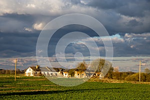 Landscape with cereal field, old farm house and blue sky