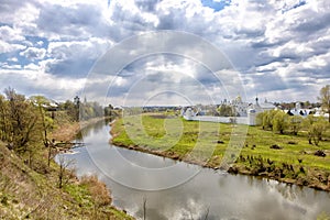 Landscape with cloudy sky, river, field and church