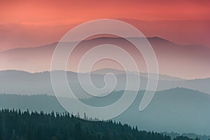 Landscape with colorful layers of mountains and haze hills covered by forest.