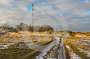 Landscape with country road leading to cellular radio tower in Ukrainian rural area