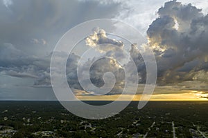 Landscape of dark ominous clouds forming on stormy sky during heavy thunderstorm over rural town area at sunset