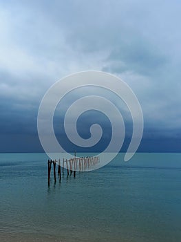 Landscape with dark sky with storm clouds over the ocean. Destroyed pier at Bophut beach on Koh Samui in Thailand. photo